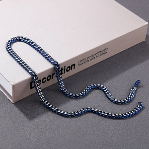 Blue and black stainless steel Cuban chain necklace on decorative book background