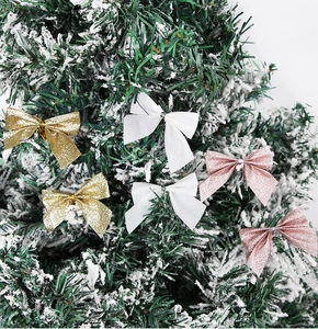Glittery gold and pink Christmas bows hanging on a snow-flocked tree branch
