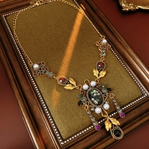 Détail macro d'un collier de perles baroques vintage avec strass colorés sur tissu vert