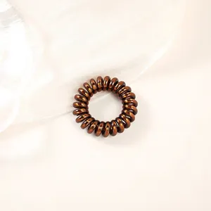 Macro shot of a brown metallic telephone cord hair tie on white silk background