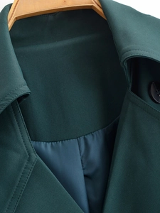 Detail of dark green trench coat lapel with black buttons on a wooden hanger