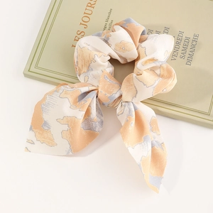 French style tie-dye bow scrunchie in orange and grey on a decorative book