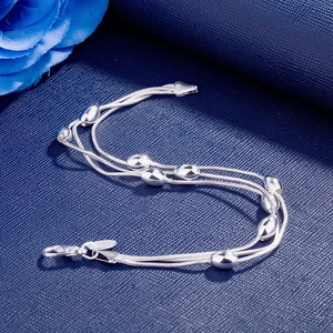 Detailed close-up of 925 silver triple-strand olive bead bracelet on blue background