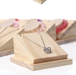 Detail view of a silver necklace with diamond pendant on a solid wood jewelry stand