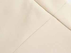 Close-up of beige woven fabric showing high-quality stitching and smooth textile texture
