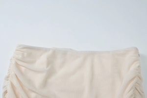 Detail of beige mesh fabric with pleated design and invisible side zipper on the dress