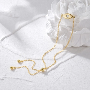 Detailed close-up of golden Evil Eye bracelet with zircon on white floral prop