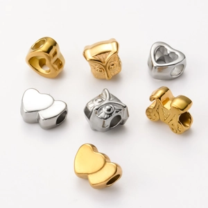 Detailed view of DIY stainless steel charm beads in heart and owl shapes, gold and silver