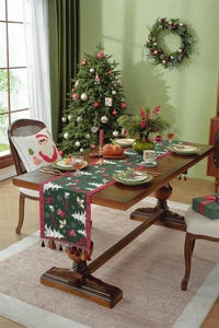Close-up of dark green Christmas table runner with tassels, reindeer and snowflake patterns