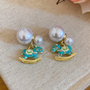 Detail view of gold hobby horse earrings with colorful enamel and white pearls