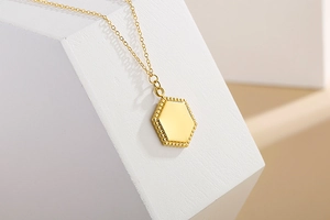 Detailed view of a gold hexagonal pendant necklace with decorative beaded edges