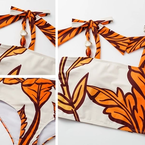Detail of beaded halter neck straps and tropical leaf print on one-piece swimsuit