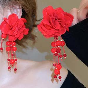 Close-up of red fabric flower earrings with beaded tassel fringe on a female model