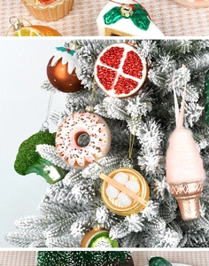 Detailed view of food-shaped glass ornaments including donuts and broccoli on a white tree