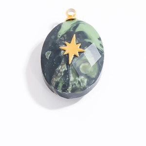 Macro detail of oval marble texture pendant with a gold star inlay and metallic loop