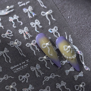 3D white bow nail art stickers with pearls and glitter on a dark textured background