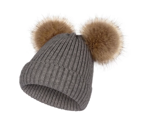 Détail du bonnet en tricot gris avec deux gros pompons marron en fourrure synthétique