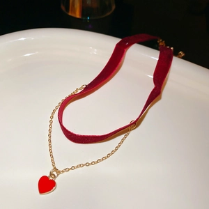 Close-up of a double-layer choker with a red velvet ribbon and a gold heart pendant