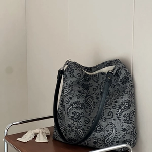 Close-up of ethnic paisley floral embroidery on black linen tote with leather straps