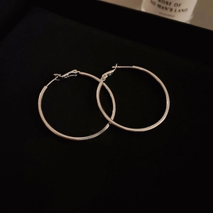 Close-up of polished silver hoop earrings on a black background with elegant lighting