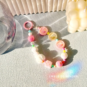 Detail of pink beaded phone charm with plush pompom and resin smiley face beads