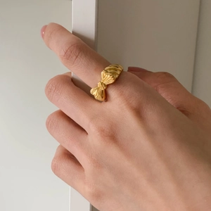 Elegant 925 sterling silver bow ring with polished gold finish on hand against white