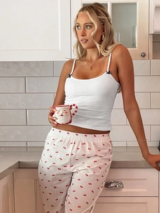 Détail du caraco blanc avec nœud noir et pantalon imprimé cerise rouge dans une cuisine
