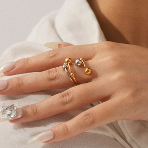 Detailed view of bicolor gold and silver steel rings with spherical bead design on hand