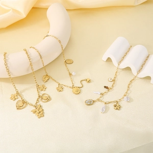 Détail de colliers en acier doré avec pendentifs romantiques en émail fleurs et papillons