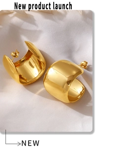 Close-up of polished gold-plated C-shape chunky hoop earrings on white silk