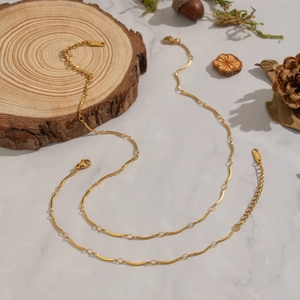 Minimalist double-layer 18K gold plated stainless steel necklace on white marble