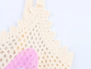 Detail of handmade crochet knit top showing soft beige texture and pink pattern weave