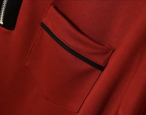 Detail of burgundy polo shirt with honeycomb texture, zipper collar and black piping pocket