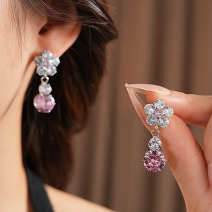 Macro shot of elegant flower-shaped earrings featuring pink and white zircon crystals