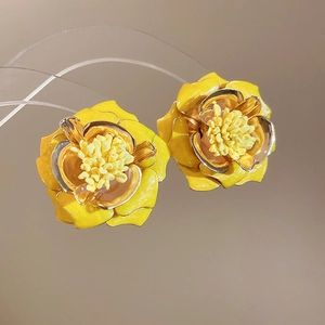 Détail de boucles d'oreilles fleurs jaunes 3D avec bordure dorée et pétales vifs