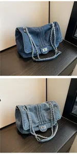 Detail view of denim tote bag with silver chain strap and metal lock closure