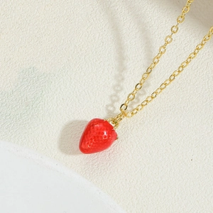 Detailed view of a red strawberry pendant with golden chain and realistic seed texture