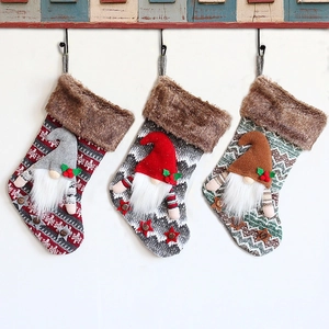 Three hanging Christmas stockings with plush gnomes in grey red and brown knitted patterns