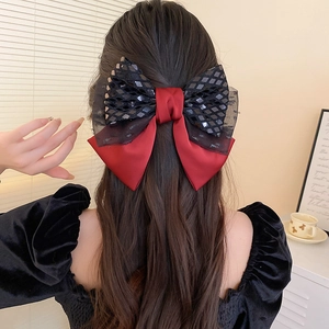 Detail of red satin and black sequin lace bow hair clip worn on model hair