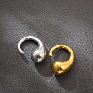 Close-up of teardrop-shaped gold and silver earrings on dark leather texture