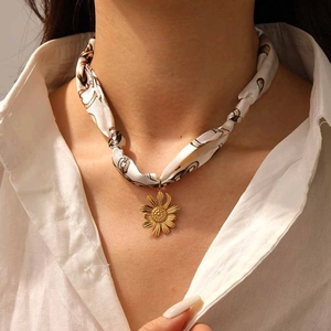 Détail d'un collier foulard en soie avec pendentif tournesol doré porté au cou