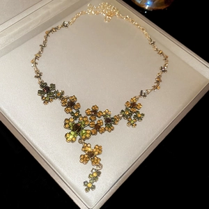 Detail of vintage flower necklace with green and amber crystals in a premium gift box