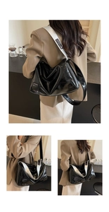 Detail of glossy black Boston bag with contrasting silver shoulder strap and woven label