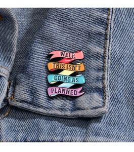 Detail of colorful enamel pin with quote on denim jacket collar for backpack decor