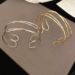 Detail of irregular multilayer metal open bangles in gold and silver finish