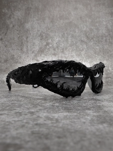Detail of avant-garde black sunglasses with organic fluid lava textured frames