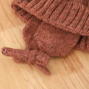 Close-up of caramel knit winter hat featuring ribbed texture and side bow detail