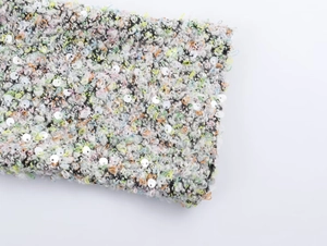 Détail du tissu bouclé multicolore avec décoration de paillettes argentées scintillantes