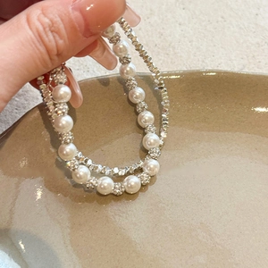 Detail view of a double-layered pearl and faceted silver beaded bracelet in French style