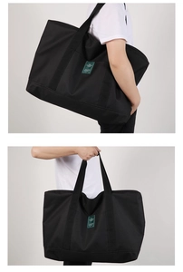 Detail of a large black travel tote bag showing durable nylon material and green label